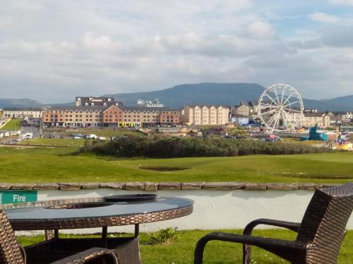 a table with two chairs and a ferris wheel at Atlantic Point Stunning Sea View in Bundoran