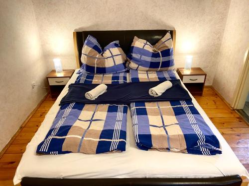 a bed with blue and white plaid sheets and pillows at Goldschmiedt Vendégház in Pálköve
