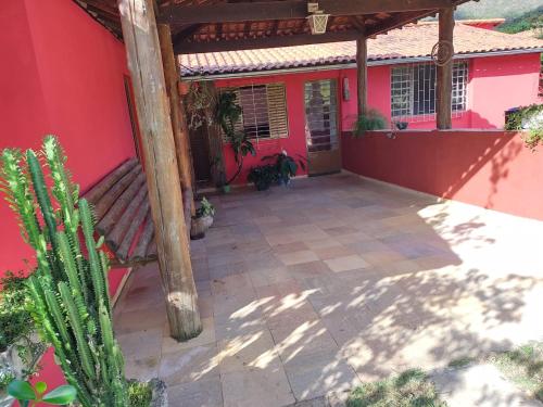 una casa roja con dos perros sentados en un patio en Recanto da Serra, en São Thomé das Letras