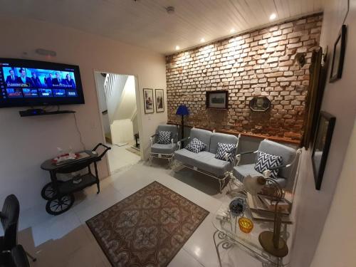 a living room with couches and a tv and a brick wall at Hostel Pousada Rheingantz Rio Grande in Rio Grande