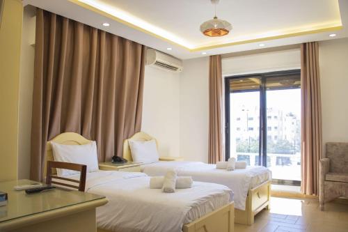 um quarto de hotel com duas camas e uma janela em Irbid Plaza Hotel em Irbid