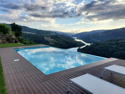 a swimming pool on a roof with a view of a river at Douro Mesio Guest House in Resende