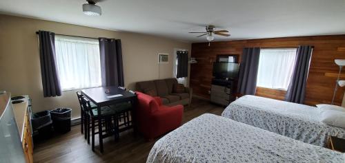 a hotel room with two beds and a desk and a couch at Fair Isle Motel in Whycocomagh