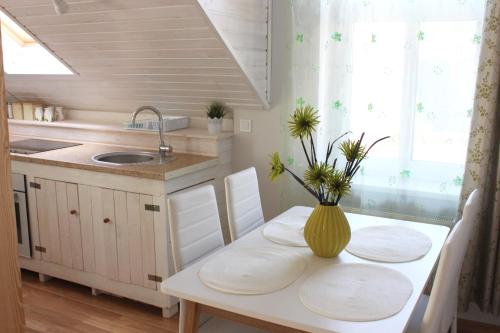 eine Küche mit einem Tisch und einer Blumenvase darauf in der Unterkunft Apartamenti Starp Krastiem in Liepāja