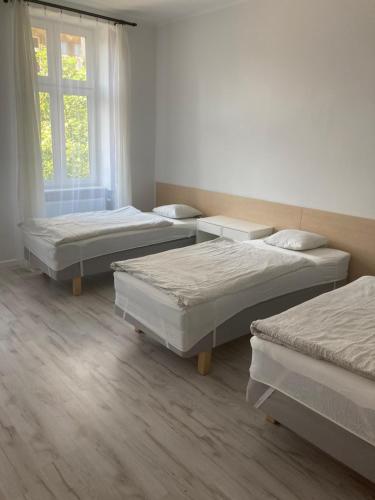 Habitación con 3 camas y ventana en Apartamenty przy Starym Rynku, en Poznan