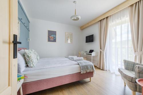 a bedroom with a bed and a desk and a window at Panocek i Babka in Białka Tatrzanska