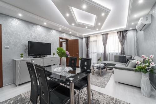 City Apartments - a brand new luxury & comfy. في أسينوفغراد: غرفة معيشة مع طاولة طعام وتلفزيون
