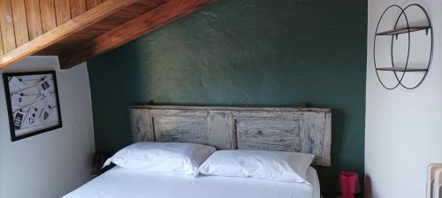a bedroom with a white bed with a green wall at Rustico La Colonna - Tremosine sul Garda in Tremosine Sul Garda