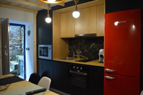 a kitchen with wooden cabinets and a red refrigerator at Casa do Amieiro, Cantinho do Céu in Casal do Rei