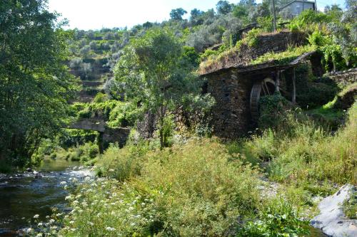 a stone building next to a river with a bridge at Casa do Amieiro, Cantinho do Céu in Casal do Rei