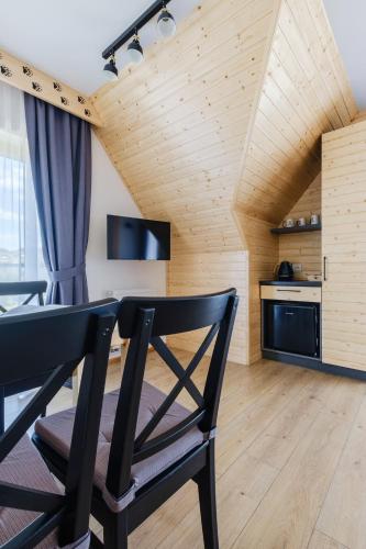 a kitchen with a wooden ceiling and a black chair at Panocek i Babka in Białka Tatrzanska