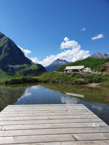 a wooden dock on a river with mountains in the background at Bichlhof in Kaisers