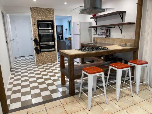 a kitchen with a stove and two stools in it at Tamborine Accommodation 84 Eagle Heights Road 6 Bedroom 3 Baths Parking Complete Holiday Home in Mount Tamborine