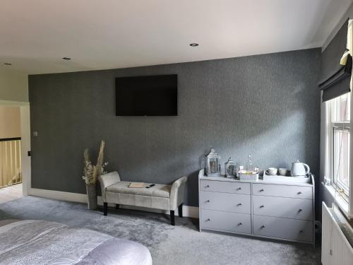 a bedroom with a dresser and a tv on a wall at Rainworth Lodge in Nottingham