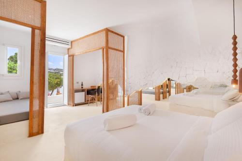 1 dormitorio con 2 camas blancas y espejo en Faos Exclusive Suites, en Ornos