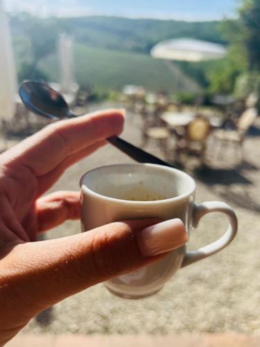 a person is holding a cup of coffee at LOCANDA PODERE LE VIGNE in Radda in Chianti