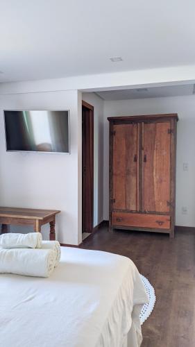 a bedroom with a white bed and a wooden cabinet at Pousada Pénareia in Morro de São Paulo