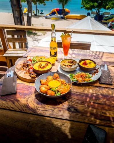 a table with plates of food and a bottle of beer at Evasion en plein cœur de la ville T3 Jacuzzis Sauna et piscine au centre de Port-Louis in Port-Louis