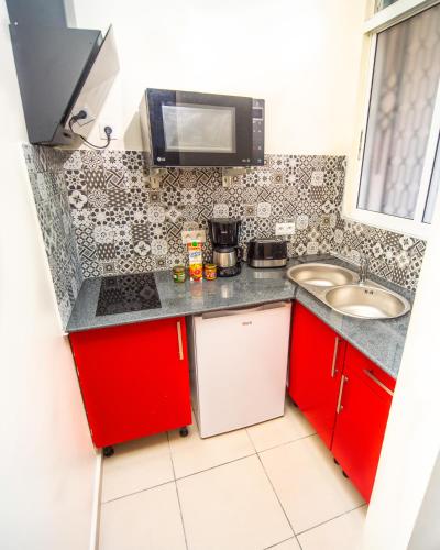 a small kitchen with red cabinets and a sink at Evasion en plein cœur de la ville Studio Jacuzzis Sauna et piscine au centre de Port-Louis in Port-Louis