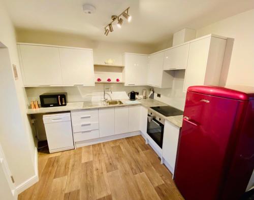 a kitchen with white cabinets and a red refrigerator at Folly View - Settle in Settle