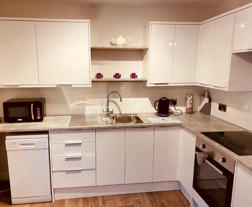 a white kitchen with white cabinets and a sink at Folly View - Settle in Settle