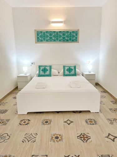 a large white bed in a room with two tables at Cocciu D'Amuri in Olbia