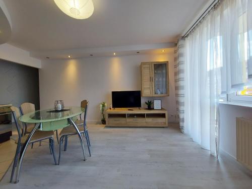 ein Wohnzimmer mit einem Tisch und einem TV in der Unterkunft Apartament Wenedów in Koszalin