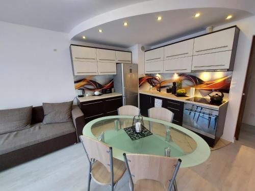 eine Küche und ein Wohnzimmer mit einem Glastisch und Stühlen in der Unterkunft Apartament Wenedów in Koszalin