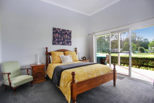 a bedroom with a bed and a chair and a window at Black Possum Cottage Views of the Bay in Pindimar