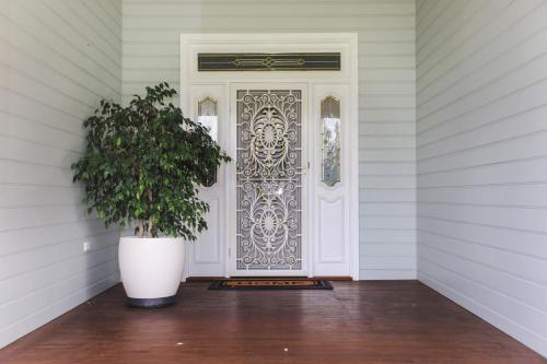 a white door with a plant in front of it at Black Possum Cottage Views of the Bay in Pindimar