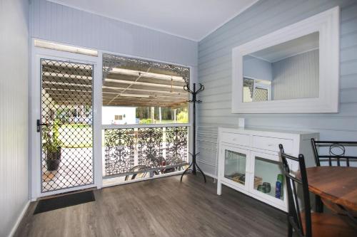 a dining room with a table and a door to a balcony at Black Possum Cottage Views of the Bay in Pindimar