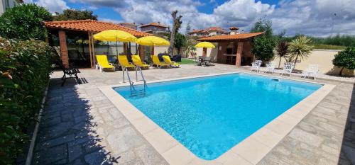 a swimming pool with chairs and umbrellas next to a house at Afonso's House Alpendurada in Memorial