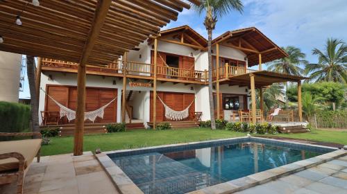 a house with a swimming pool in front of it at Vila Gará Kite House - Ilha do Guajiru in Itarema