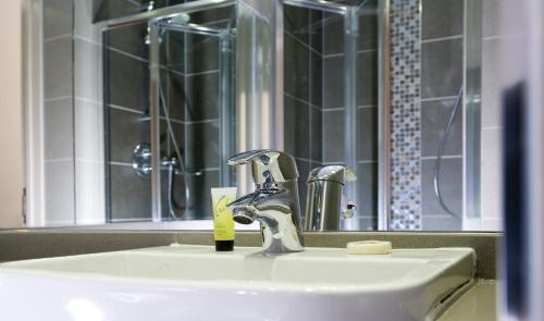 La salle de bains est pourvue d'un lavabo, d'un robinet et d'un miroir. dans l'établissement London Court Hotel, à Londres
