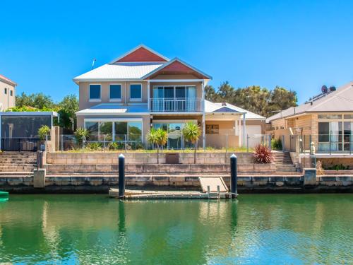 uma casa sobre a água com uma doca em "WATERLILY HOUSE" - Luxury Canal House, Jetty, Dog & Child Friendly - Sleeps 14 em Mandurah