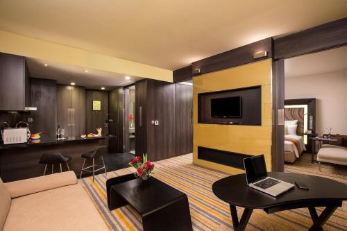 a living room with a couch and a laptop on a table at Novotel Kolkata Hotel and Residences in Kolkata