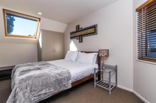 a small bedroom with a bed and a window at Twin Peaks Lakeside Inn in Taupo