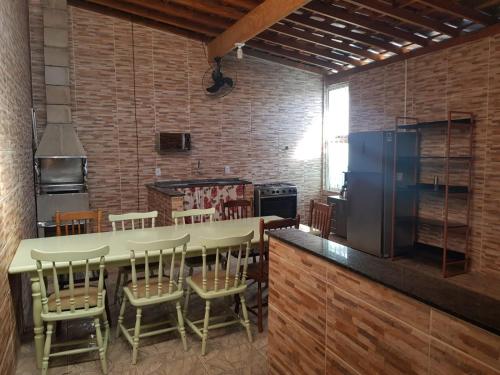 eine Küche mit einer großen Theke mit Stühlen und einem Kühlschrank in der Unterkunft Casa 1km Anhanguera e Churrasqueira Wi-Fi in Louveira