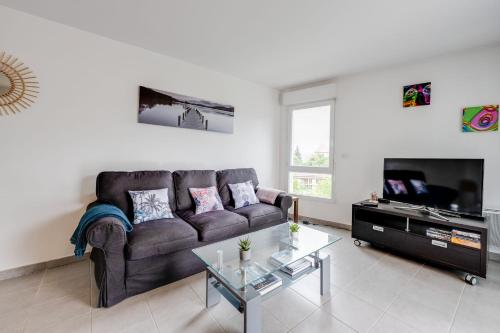 - un salon avec un canapé brun et une télévision dans l'établissement Le Basilique - Joli T2 de 59m proche lac et Vieille Ville, à Annecy