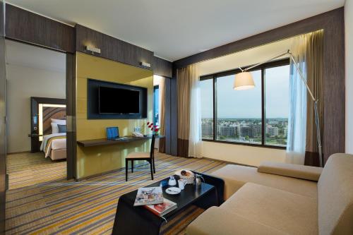 a living room with a couch and a tv at Novotel Kolkata Hotel and Residences in Kolkata