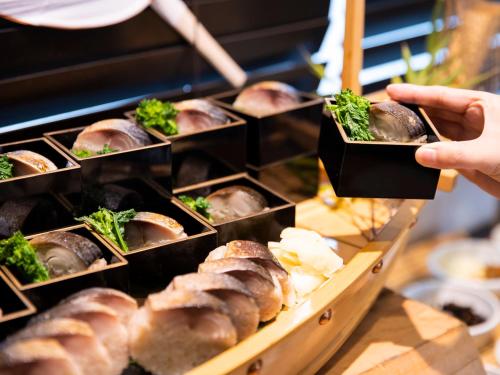 a person is reaching for a tray of food at Ariston Hotel Kyoto Jujo in Kyoto