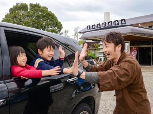 a man giving two children high five in the back of a car at Kameyama Onsen Hotel in Kimitsu