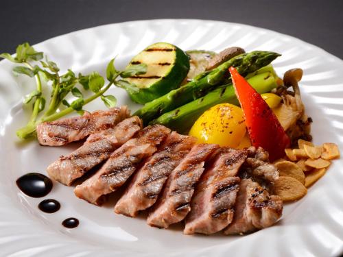 a plate of food with meat and vegetables on it at Kameyama Onsen Hotel in Kimitsu