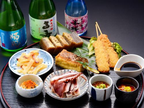a tray with different types of food and bottles of wine at Kameyama Onsen Hotel in Kimitsu