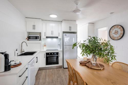 a kitchen with white cabinets and a wooden table at Iluka Villa 1 in Iluka