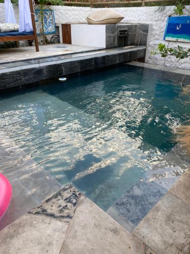 a pool with blue water and a stone floor at Pousada Fortal Preá in Prea