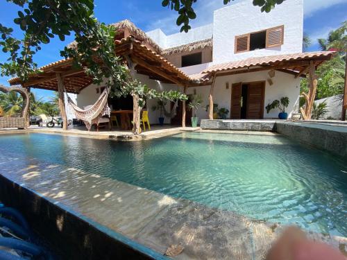 a villa with a swimming pool in front of a house at Pousada Fortal Preá in Prea