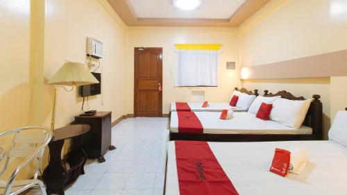 a hotel room with two beds and a television at RedDoorz Plus near Municipality of Luisiana Laguna in Laguna
