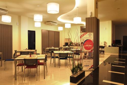 un comedor con mesas y sillas en un restaurante en Cordela Hotel Medan en Medan