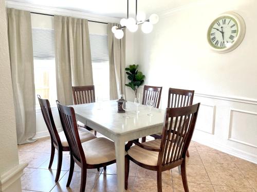 a dining room table with chairs and a clock on the wall at Modern Chic Home in Channelview